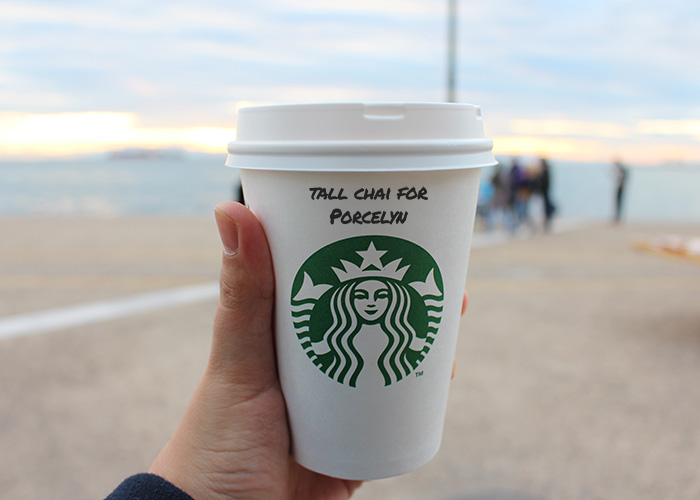 How Many Calories In A Chai Latte From Starbucks? (2023) 3 person holding tall chai latte in paper cup from Starbucks