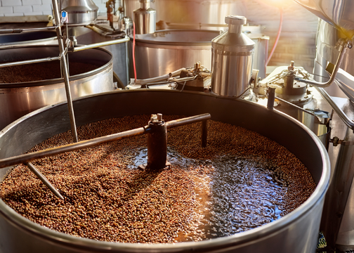 Large Stainless Steel Fermentation Tank Filled With Grains And Liquid, Equipped With Mechanical Stirring Arms And Fluid Transfer Piping. 